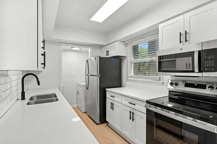 Bright modern kitchen with sleek white cabinetry, stainless steel appliances, and elegant black fixtures.