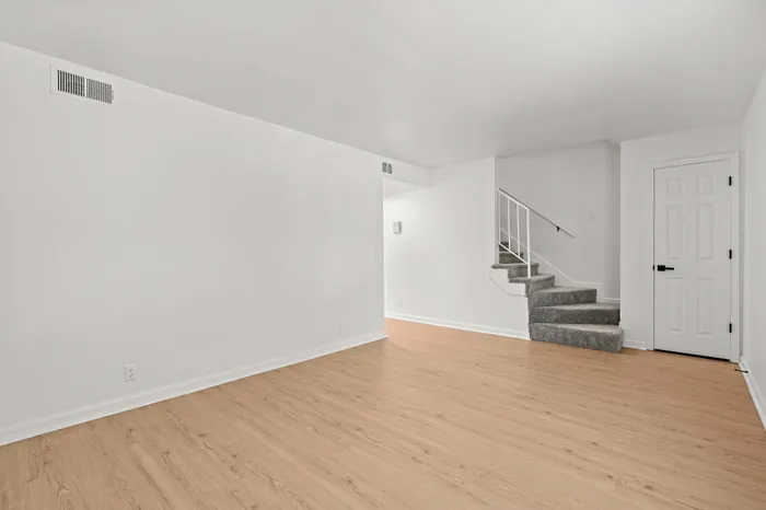 Bright, airy living space with wooden flooring and modern carpeted stairs, perfect for comfortable and stylish living.