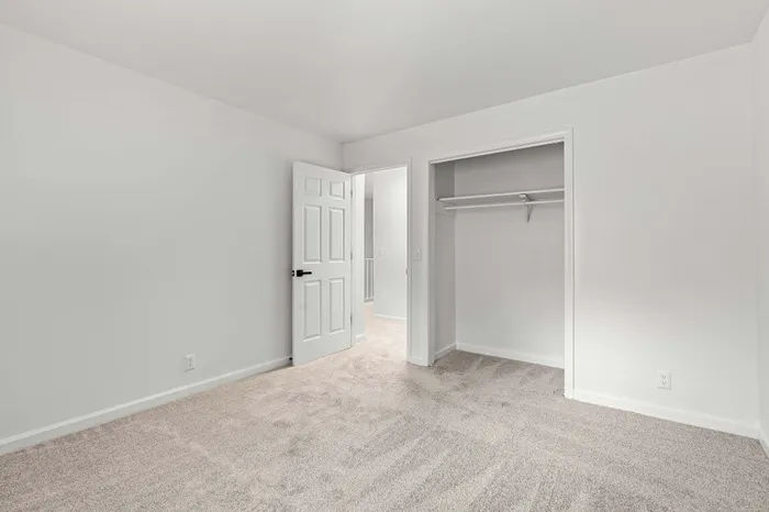 Bright and airy bedroom with plush carpeting and a spacious closet for optimal storage.