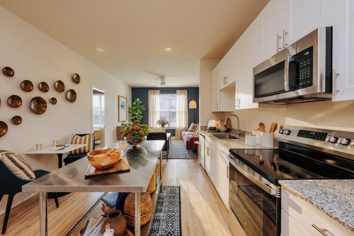 Modern open-concept kitchen and living room with stylish decor, stainless steel appliances, and abundant natural light.
