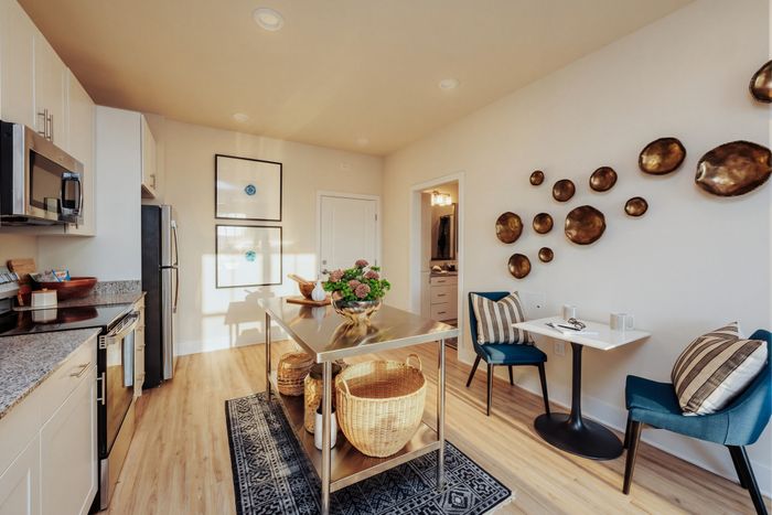Chic modern kitchen with stainless steel appliances, granite countertops, and stylish wall decor, featuring a cozy dining nook with elegant seating.