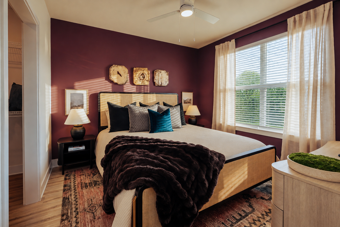 Elegant bedroom with chic decor, featuring a cozy bed with plush pillows, stylish wall art, and a large window filling the room with natural light.