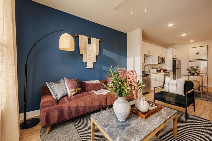 Chic apartment with a modern open-plan living area, featuring a cozy sofa against a stylish blue accent wall, and a sleek kitchen with stainless steel appliances.