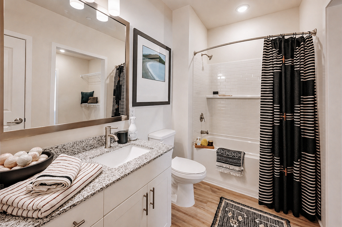 Modern bathroom featuring sleek granite countertops, elegant striped curtains, and stylish decor accents.