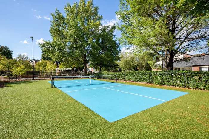 Lush outdoor tennis court set against a backdrop of vibrant greenery, offering a serene and sporty escape.