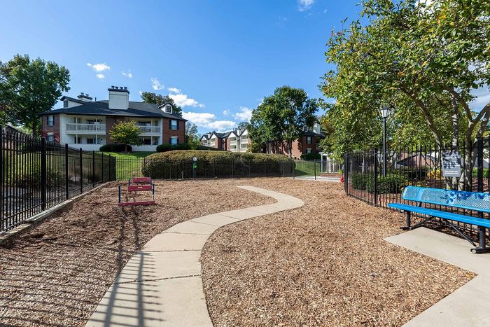 Charming apartment complex featuring lush greenery and a cozy pet-friendly area, perfect for outdoor enjoyment.