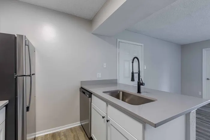 Modern kitchen featuring sleek stainless steel appliances, elegant gray countertops, and pristine white cabinetry.