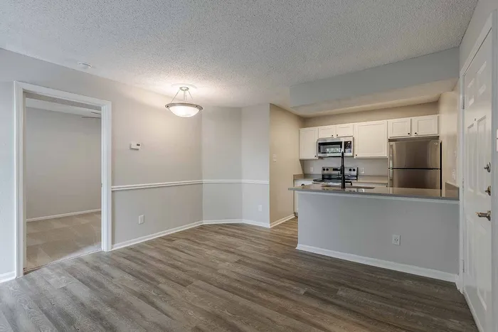 Modern apartment interior featuring an open-plan kitchen with stainless steel appliances, stylish lighting, and elegant wooden flooring.