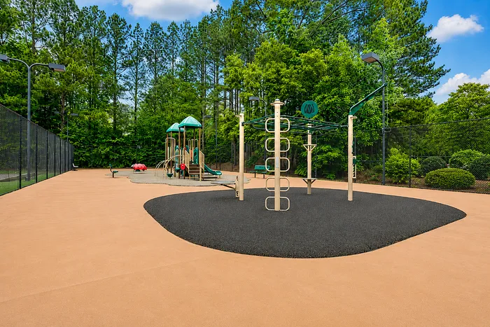 Inviting outdoor playground with modern equipment, surrounded by lush green trees, perfect for family fun.