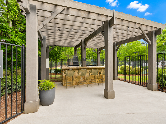 Charming outdoor pergola with bar area set amid lush greenery, perfect for entertaining.