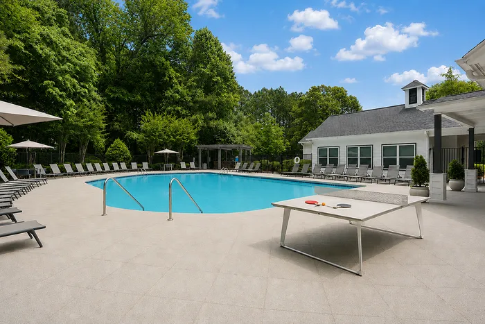 Inviting outdoor pool area with lounge chairs, surrounded by lush greenery and a charming pavilion, perfect for relaxation and leisure.