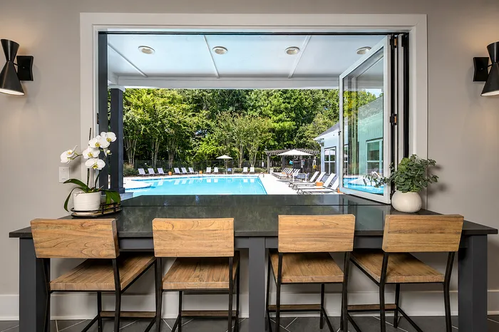 Modern open kitchen with a view of the luxurious pool area, featuring wooden bar stools and elegant decor.