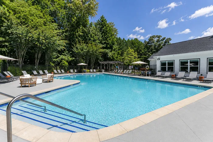 Luxurious outdoor pool area with inviting sun loungers, surrounded by lush greenery and umbrellas, perfect for relaxation.