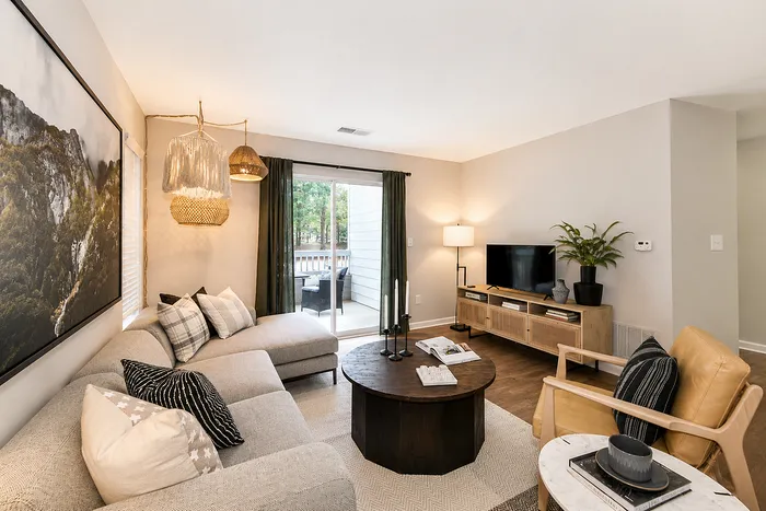 Chic, modern living room with cozy sectional, elegant artwork, and large sliding door leading to a tranquil outdoor view.