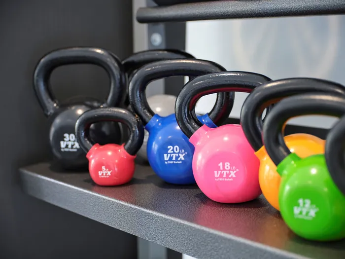 Vibrantly colored kettlebells neatly arranged on a sleek gym shelf, showcasing various weights for a dynamic workout space.