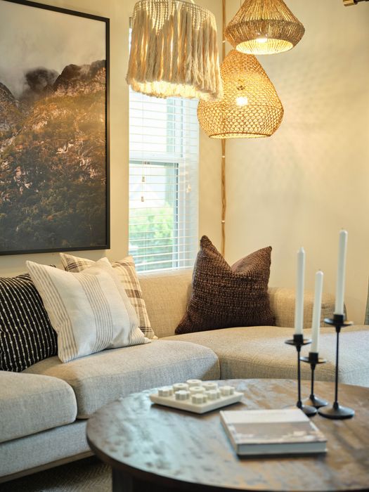 Charming living space with cozy beige sofa adorned with elegant pillows, warm woven pendant lights, and artistic decor creating an inviting ambiance.