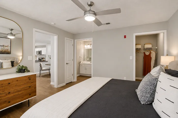 Elegant bedroom with cozy bedding, stylish decor, and a spacious walk-in closet, leading to a modern bathroom and dining area.