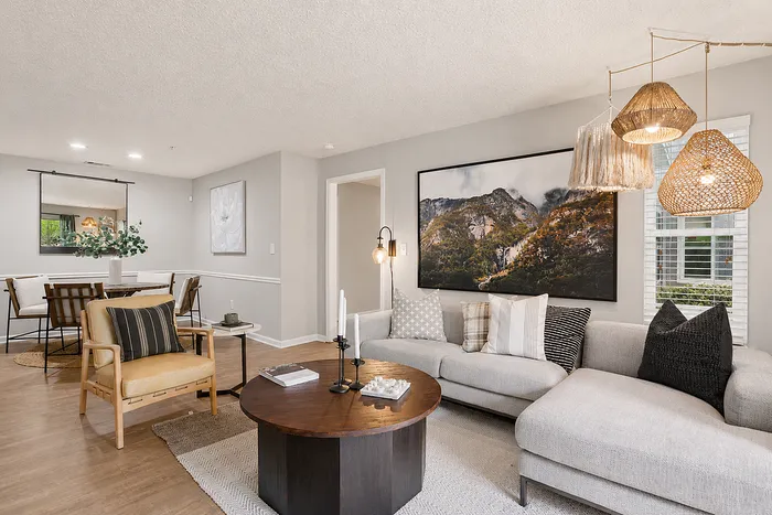Elegant living room showcasing a modern gray sofa, woven pendant lights, and a rustic round coffee table in an open-concept layout.