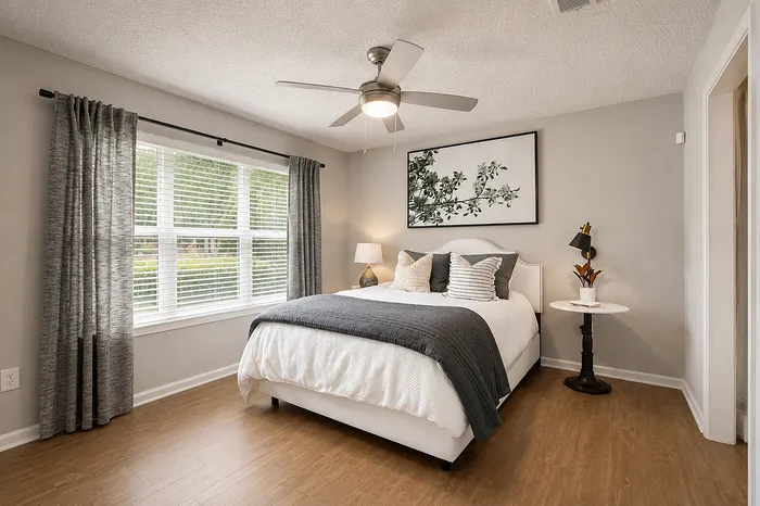 Chic bedroom with elegant decor, featuring a cozy bed, stylish bedside lamp, and large windows for abundant natural light.