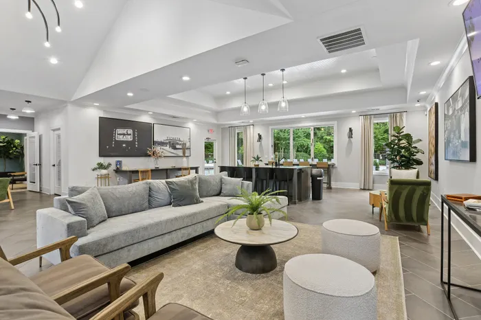 Elegant and spacious living area with modern decor, featuring a plush gray sofa, stylish lighting, and large windows offering serene garden views.