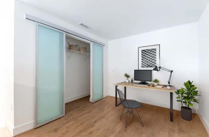 Bright modern office space with sleek desk, stylish chair, and sliding closet doors. Ideal for productivity and creativity.
