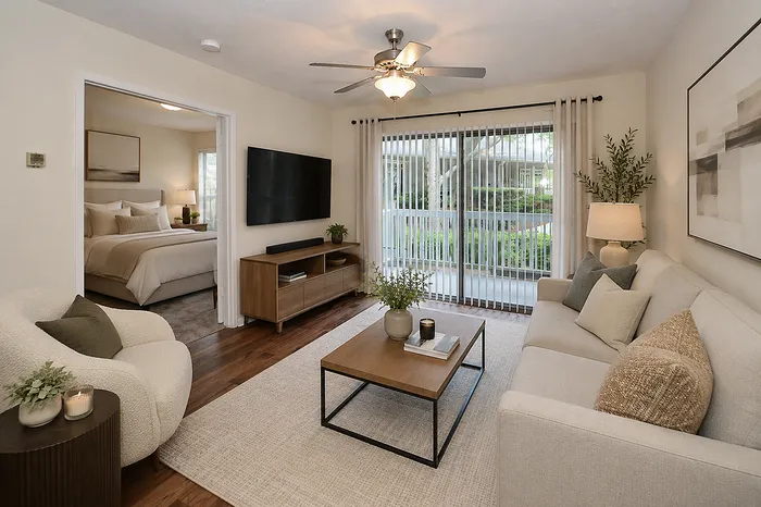 Cozy living room with elegant decor, modern furniture, and a view into a tranquil bedroom through an open door, bathed in natural light.
