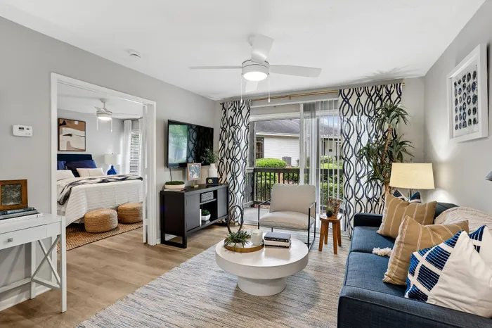 Inviting living room with elegant decor, featuring a cozy seating area, large TV, and sliding glass doors opening to a lush garden view.