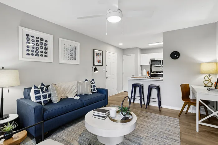 Contemporary living space featuring a chic blue sofa, elegant coffee table, and modern kitchen with bar seating, perfect for urban living.