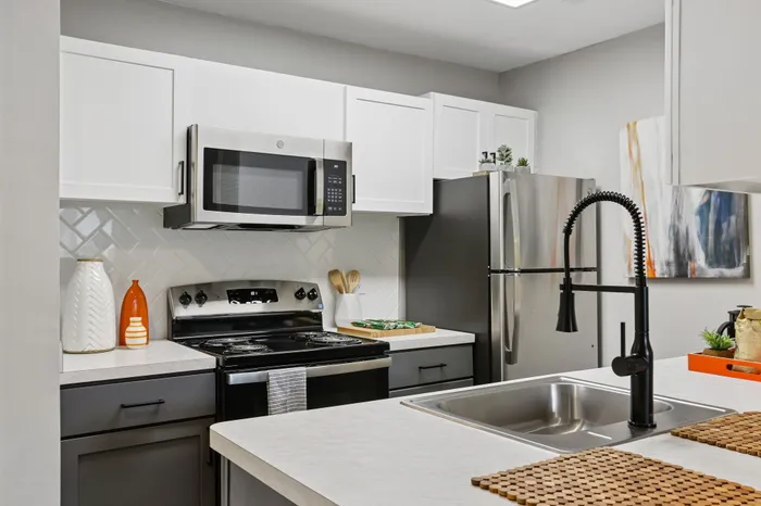 Modern kitchen with sleek stainless steel appliances, elegant white cabinetry, and a stylish backsplash.