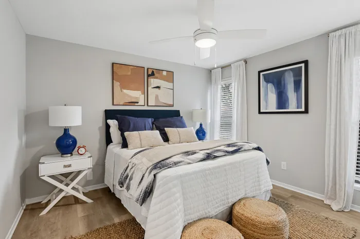 Inviting bedroom with stylish decor featuring a cozy bed, elegant blue accents, and modern artwork, creating a tranquil sanctuary.