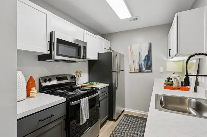 Modern kitchen design featuring sleek stainless steel appliances, bright white cabinetry, and elegant countertops, perfect for a stylish apartment.
