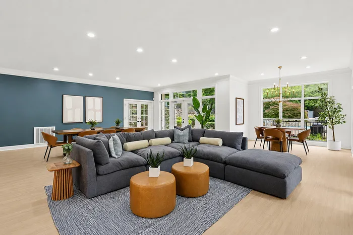 Spacious modern living room with elegant sectional sofa, stylish decor, and ample natural light from large windows, perfect for entertaining.
