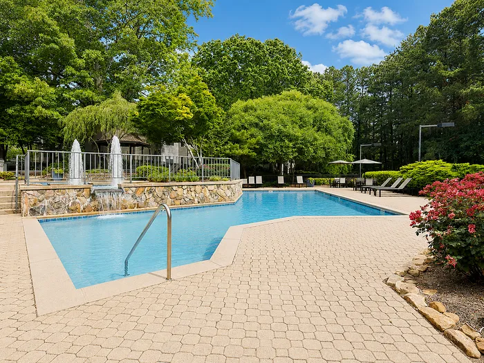 Inviting outdoor pool area surrounded by lush greenery, featuring elegant stonework and comfortable loungers for a perfect relaxing escape.