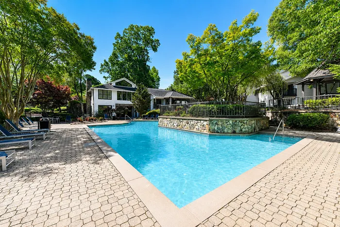 Stunning apartment complex with a sparkling pool, surrounded by lush greenery and elegant architecture, perfect for relaxation and luxury living.
