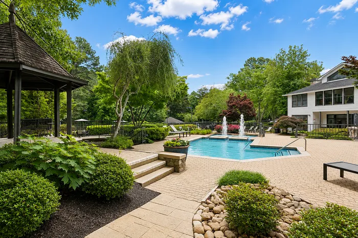 Lush outdoor retreat with a stylish pool area, scenic gazebo, and vibrant greenery, perfect for relaxation.
