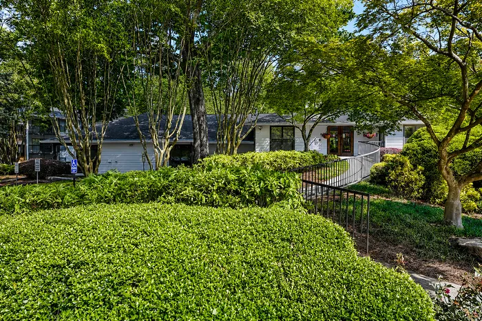Charming single-story home with lush landscaping, mature trees, and inviting front entrance, perfect for nature lovers.