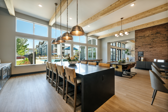 Luxurious dining area with high ceilings, modern lighting, and large windows providing ample natural light; perfect for entertaining.