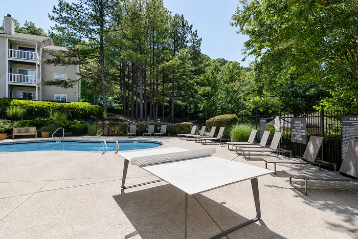 Relaxing outdoor pool area surrounded by lush greenery and comfortable lounge seating, perfect for sunny days.