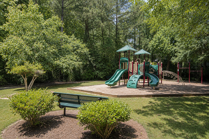 Inviting playground surrounded by lush greenery, featuring slides and climbing structures, perfect for family fun and leisure.