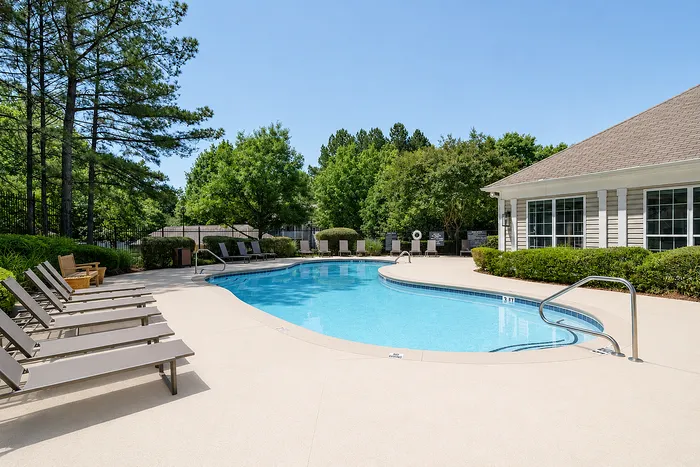 Inviting outdoor pool surrounded by lush greenery and comfortable lounge chairs, ideal for relaxation and leisure.