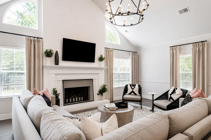 Elegant living room with vaulted ceiling, modern chandelier, cozy fireplace, and stylish sectional sofa.