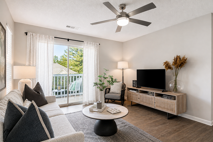 Contemporary living room with stylish furniture, decorative elements, and natural light streaming through glass doors leading to a balcony.