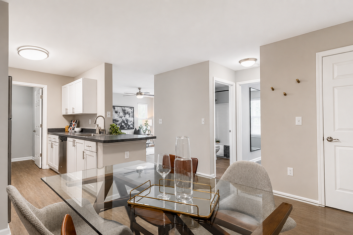 Contemporary apartment interior featuring a stylish open kitchen with sleek countertops, connected to a cozy dining area. Modern lighting and elegant decor create an inviting ambiance.