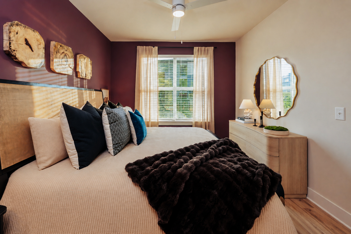 Luxurious bedroom with plush bedding, a stylish upholstered headboard, and elegant decor, bathed in natural light from large windows with chic curtains.