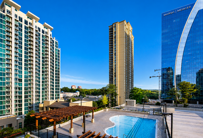 Luxurious high-rise apartments with a stunning cityscape view, featuring a modern swimming pool and vibrant surroundings.