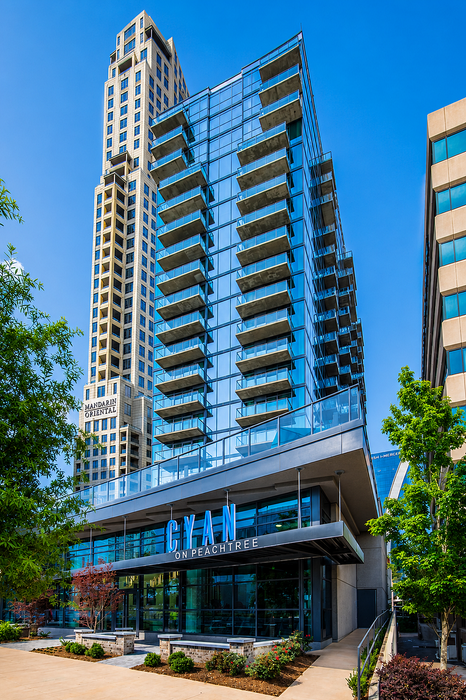 Modern glass apartment building with spacious balconies and lush greenery at the entrance. Prime location with stunning city views.
