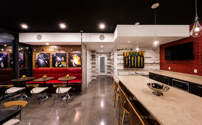 Chic apartment lounge with modern art, sleek red seating, and industrial lighting, perfect for stylish gatherings.