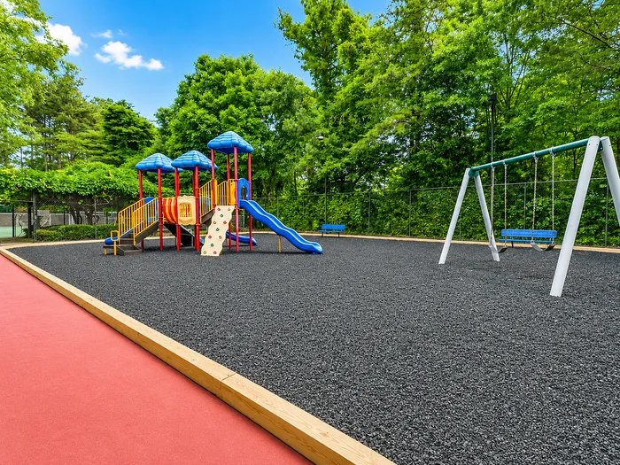 Vibrant playground with colorful slides, swings, and climbing wall, surrounded by lush greenery and perfect for family fun.