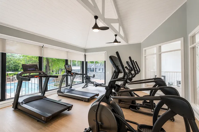 Bright and modern gym with cardio equipment and stunning pool view, perfect for fitness enthusiasts.