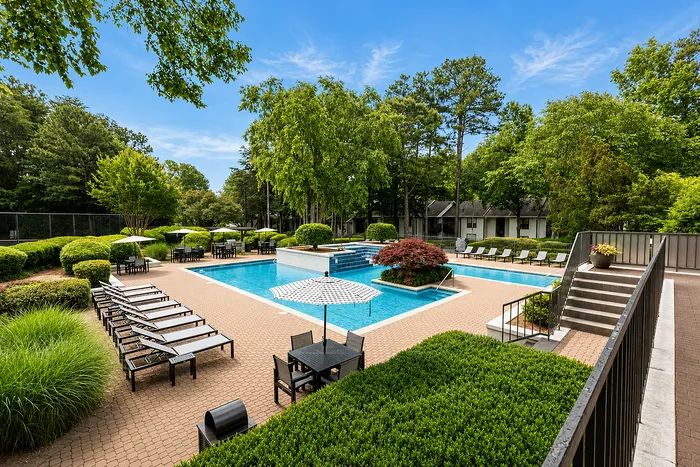 Inviting outdoor pool area surrounded by lush greenery and stylish loungers, perfect for relaxation and leisure.